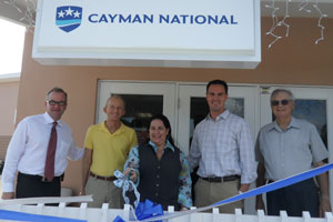 Cayman National Bank Executive Vice President, Mr. Brian Esau, Chairman of the Board of Directors of Cayman National Corporation (CNC), Mr. Truman Bodden, and Manager of the Cayman Brac and Little Cayman Customer Service Centres, Mrs. Zanda Scott cuts the ribbon to mark the official opening of the expanded Little Cayman Customer Service Centre, while Blossom Village Landlord, Mr. Kyle Hooker, Pastor of the Little Cayman Baptist Church, Reverend James Barron look on.